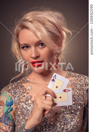 Blonde woman with a beautiful hairstyle and perfect make-up is posing with playing cards in her hands. Casino, poker. Blonde woman with a beautiful hairstyle and perfect make-up is posing with playing cards in her hands. Casino, poker. 106692090