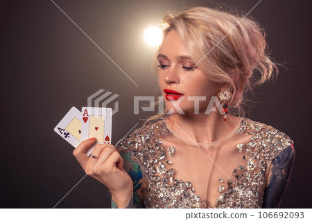 Blonde woman with a beautiful hairstyle and perfect make-up is posing with playing cards in her hands. Casino, poker. 106692093