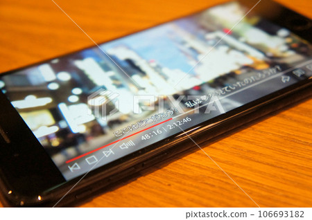Watching videos on a smartphone in a cafe 106693182