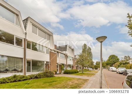 a street with cars parked on the side and buildings in the back ground, some trees are growing next to the sidewalk 106693278