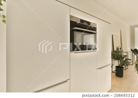 a kitchen and dining area in a modern apartment with white walls, wood flooring and an oven on the wall a kitchen and dining area in a modern apartment with white walls, wood flooring and an oven on the wall 106693312