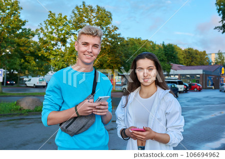 Outdoor portrait of teenagers students, smiling guy and girl with backpack looking at camera Outdoor portrait of teenagers students, smiling guy and girl with backpack looking at camera 106694962