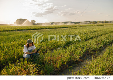 Professional woman farmer with digital tablet works in field. Agricultural business concept Professional woman farmer with digital tablet works in field. Agricultural business concept 106696376