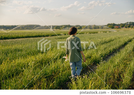Back view of female farmer walks across a field during harvesting. Agricultural occupation concept 106696378