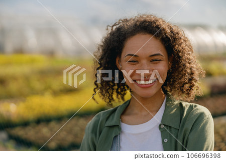 Professional smiling female farmer standing on the field on greenhouses background 106696398