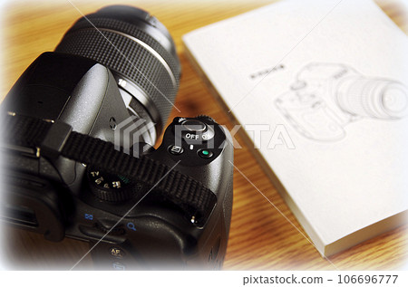 Camera and booklet placed on a wooden table (illustration style) Camera and booklet placed on a wooden table (illustration style) 106696777