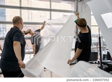 Car service worker team preparing armored protective film for applying 106697092