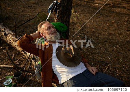 Elderly man hiker rest on log surrounded pine forest environment 106697120