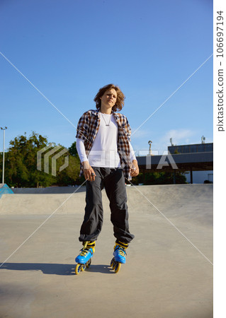 Young teen in rollerblades making stunt on cement ramp in skate park Young teen in rollerblades making stunt on cement ramp in skate park 106697194