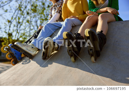 Crop view of rollerskaters team of teenage people sitting on ramp 106697195