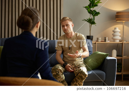 Military man hugging himself suffering from bad memories during therapy session 106697216