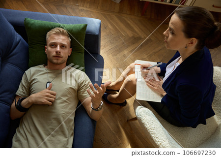 Frustrated sad soldier with ptsd talking at psychiatrist during therapy session 106697230