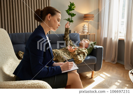 Man soldier with PTSD lying on sofa talking to psychotherapist 106697231