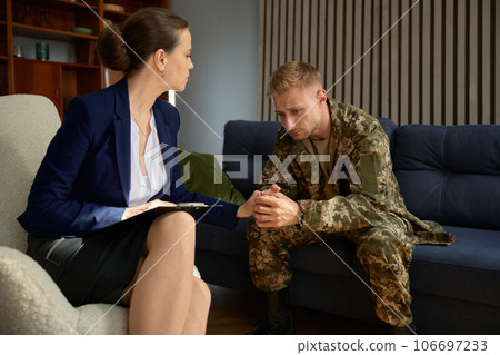 Psychologist holding hand of war veteran or soldier talking about his trauma 106697233