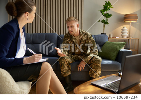 Worried soldier talking to doctor psychologist during therapy session 106697234