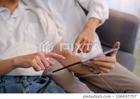 Passionate young gay couple relaxing on couch and browsing internet on digital tablet. LGBT, love and lifestyle concept Passionate young gay couple relaxing on couch and browsing internet on digital tablet. LGBT, love and lifestyle concept 106697707