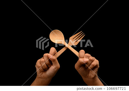 Hands holding spoon and fork over black background. Gesture of eating, dinning and cooking 106697721