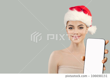 Christmas woman. Cheerful Santa model showing smartphone with empty white screen display,  106698131