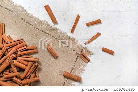 Tabletop view - Heap of cinnamon bark sticks on linen tablecloth and white stone desk Tabletop view - Heap of cinnamon bark sticks on linen tablecloth and white stone desk 106702430