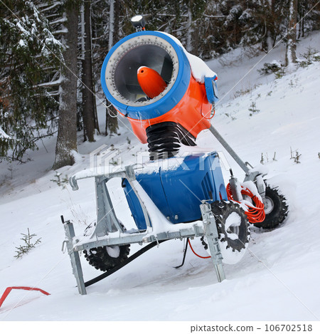 Bright orange and blue snow making cannon, trees in background Bright orange and blue snow making cannon, trees in background 106702518
