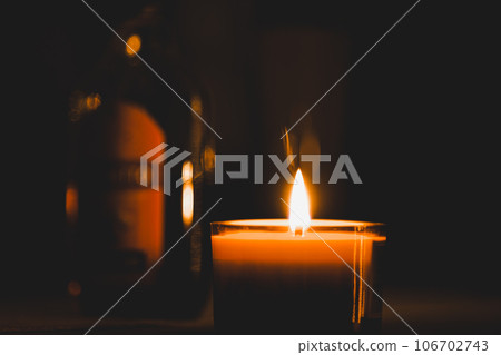 Closeup shot of a lit candle in the darkness Closeup shot of a lit candle in the darkness 106702743