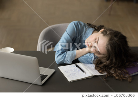 Sleepy exhausted student girl leaning head on table at laptop 106703306