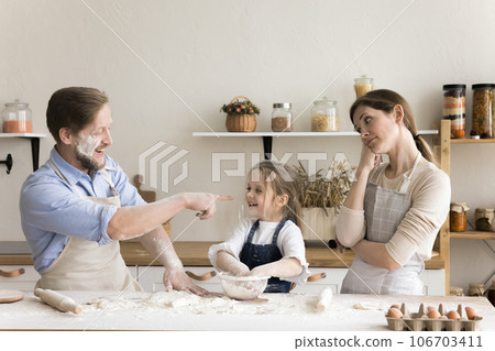 Caring bored mom watching happy toddler kid and dad baking Caring bored mom watching happy toddler kid and dad baking 106703411