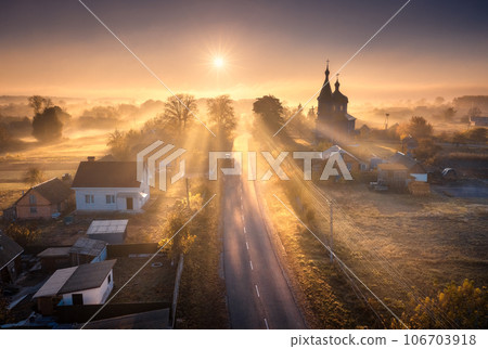 Aerial view of village in fog with golden sunbeams at sunrise Aerial view of village in fog with golden sunbeams at sunrise 106703918