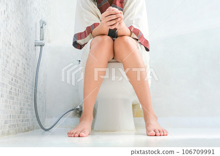 Woman sitting on the toilet bowl in the bathroom. She has stomach ache. Poor digestive system. Constipation. Diarrhea. Food poisoning. Health and medicine. Woman sitting on the toilet bowl in the bathroom. She has stomach ache. Poor digestive system. Constipation. Diarrhea. Food poisoning. Health and medicine. 106709991