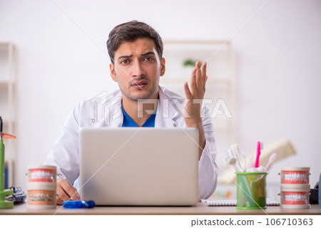 Young male dentist working in the clinic 106710363