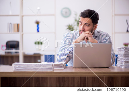 Young male employee and too much work in the office Young male employee and too much work in the office 106710390
