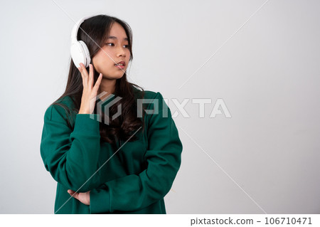 A happy attractive carefree pleased teenage girl has fun, relaxing dancing and smiling, joyfully with raised arms, being entertained and amused isolated on a white background. A happy attractive carefree pleased teenage girl has fun, relaxing dancing and smiling, joyfully with raised arms, being entertained and amused isolated on a white background. 106710471