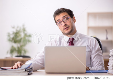 Young male employee and too much work in the office 106710950