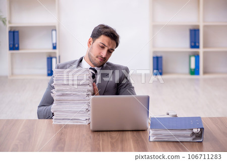 Young male employee and too much work in the office Young male employee and too much work in the office 106711283