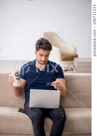 Young man holding moneybag at home Young man holding moneybag at home 106711314