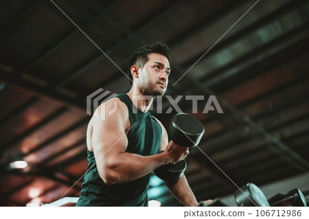 Young Asian Man Working Out with Dumbbell in a Vibrant Gym Young Asian Man Working Out with Dumbbell in a Vibrant Gym 106712986