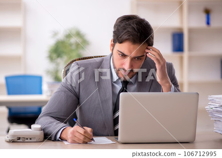 Young male employee and too much work in the office 106712995
