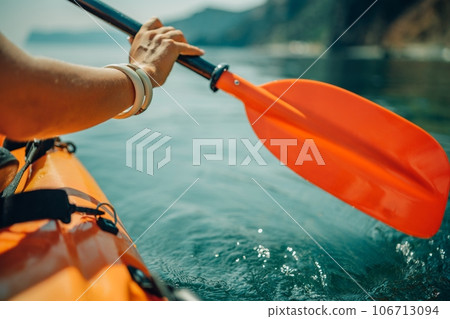 Kayak paddle sea vacation. Person paddles with orange paddle oar on kayak in sea. Leisure active lifestyle recreation activity rest tourism travel 106713094