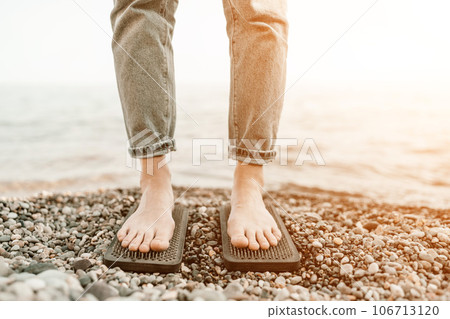 Sea Woman feet stepping on sadhu board during indian practice on the seashore. . Healthy lifestyle concept. tool for working out your inner state 106713120