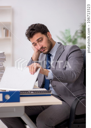 Young male employee and too much work in the office 106713523