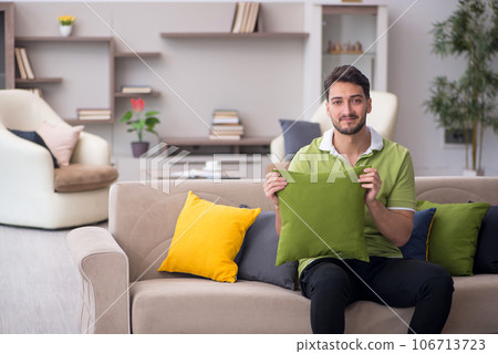 Young man with a lot of pillows sitting on the sofa 106713723