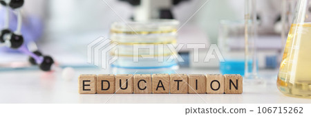 Word education assembled from wooden cubes on laboratory table with science equipment. 106715262