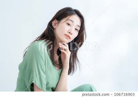 A young woman who does skin care in the white background of sunlight filtering through foliage 106716903