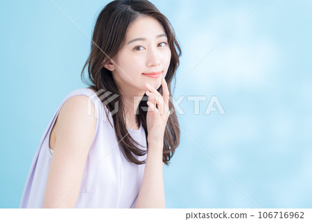 一位在陽光普照的藍色背景下做護膚的年輕女性 106716962