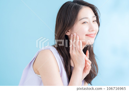 A young woman doing skin care on a blue background where the sun shines 106716965