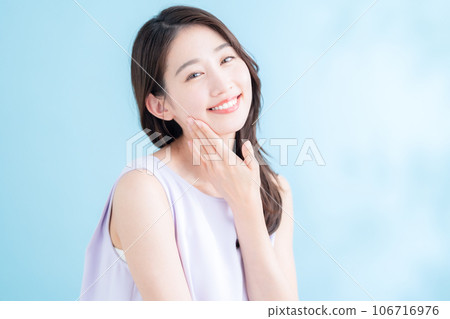 A young woman doing skin care on a blue background where the sun shines 106716976