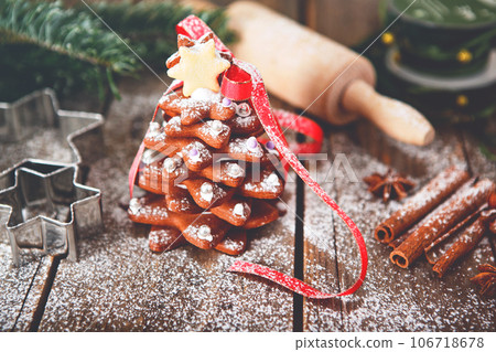 Home made baked Christmas gingerbread tree as a gift for family and friends on wooden background. With colorful lights from Christmas tree on background. With icing sugar gift for xmas 106718678