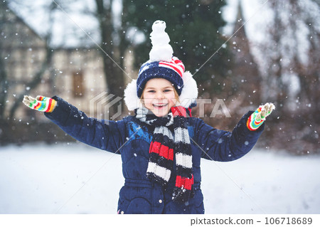 Cute little preschool girl with mini snowman on head. Adorable healthy happy child playing and having fun with snow, outdoors on cold day. Active leisure with children in winter 106718689