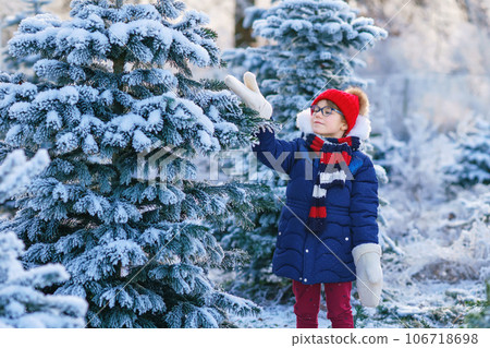 Small girl playing with snow. Happy preschool child in winter forest on snowy cold december day. 106718698