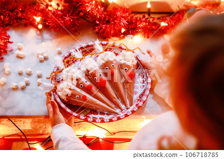 Little preschool girl holding reindeer made with chocolate cocoa powder and marshmallows. Selfmade dessert drink for children on Christmas. Little preschool girl holding reindeer made with chocolate cocoa powder and marshmallows. Selfmade dessert drink for children on Christmas. 106718785